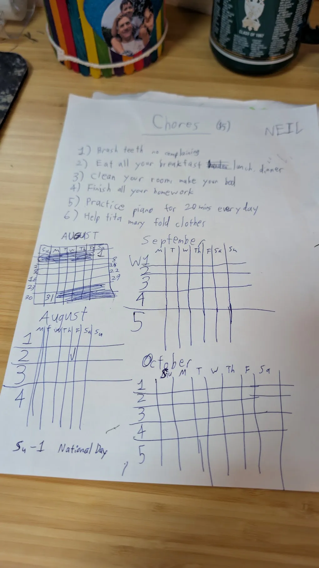 A child's handwritten chores list on a sheet of paper, headed "Chores", with six numbered jobs and hand-drawn month grids for August, September and October below it